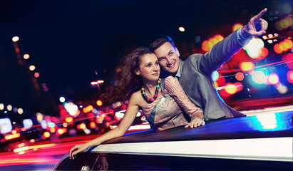 Elegant couple traveling a limousine at night - obrazy, fototapety, plakaty