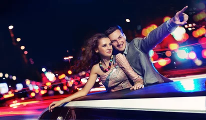 Poster Elegant couple traveling a limousine at night © konradbak