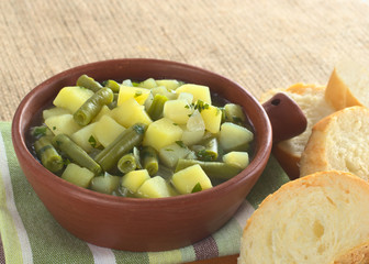 Potato-green-bean hotpot in rustic bowl with baguette
