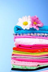 Pile of colorful clothes and flowers   on blue background
