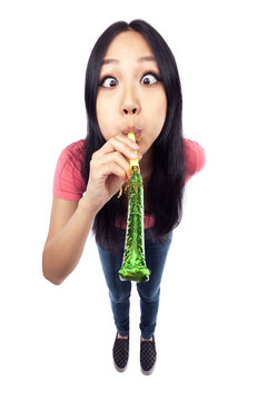 A wide angle shot of an Asian girl blowing a noise maker