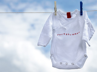 Little babygro on a clothesline in front of blue sky