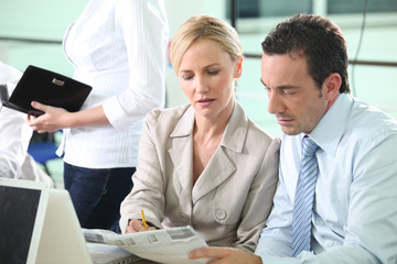 Business colleagues looking at a newspaper
