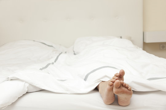 Füße schauen unter der Bettdecker heraus Stock Photo | Adobe Stock