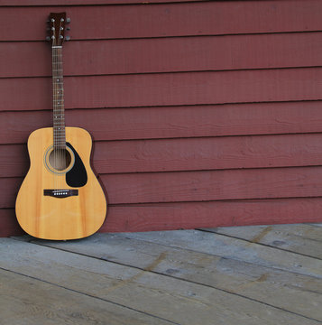 Acoustic guitar against an old plank wall.