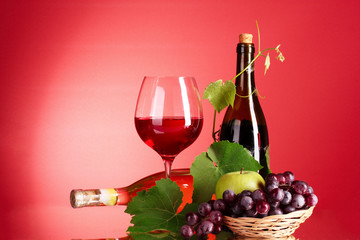 Wine and fruits on red background