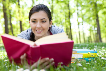 Fototapeta premium relaxed girl lying on grass with book
