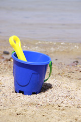 Fototapeta na wymiar blue bucket with a shovel on seacoast