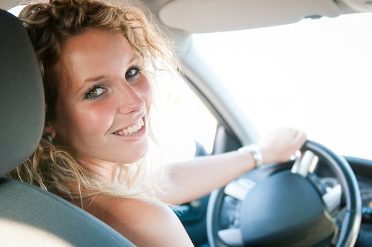 Portrait of young smiling woman inside a car