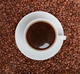 Cup of coffee sitting in a bed of coffee beans