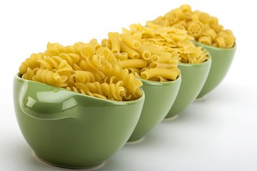 Assorted raw pasta noodles in green ceramic dish