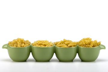 Assorted raw pasta noodles in green ceramic dish