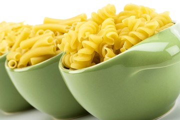 Assorted raw pasta noodles in green ceramic dish