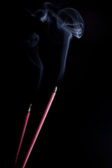 Smoke coming up from an incense stick over a black background