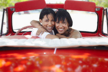 beautiful twin sisters hugging in cabriolet car