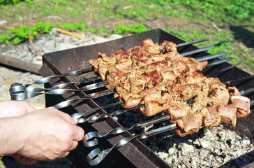Man hands grilling tasty barbecue on black coals on mangal