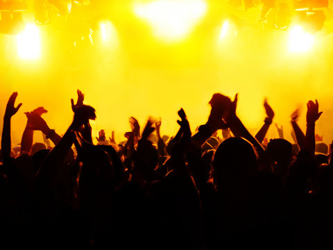 silhouettes of concert crowd in front of bright stage lights