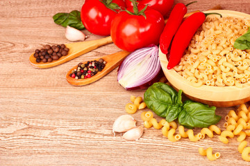 spaghetti with garlic, onion, spices  and basil on wooden table