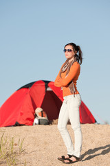 Camping happy woman outside tent on beach