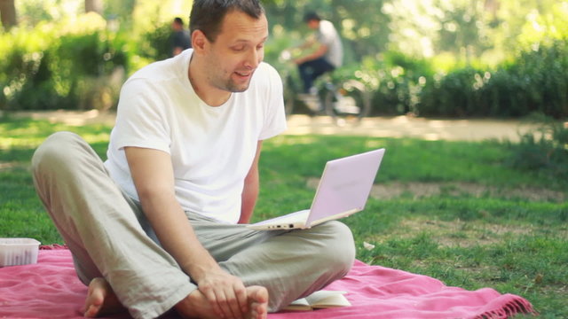 A young man chatting on laptop outdoor