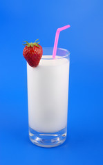 Glass of milk and strawberry on blue background