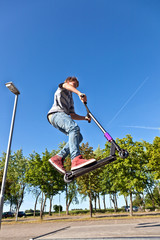 boy jumps with his scooter at the skate park