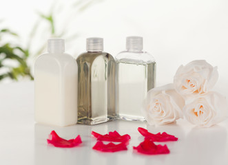 Glass flasks with white roses and pink petals