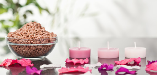 Obraz na płótnie Canvas A bowl of brown gravel with pink petals and candles