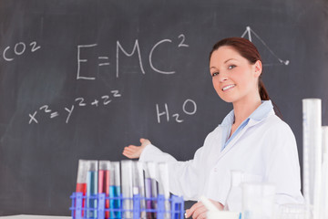 Cute scientist showing the equations on a blackboard