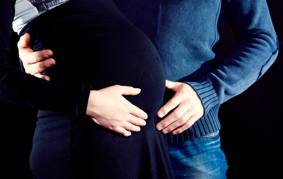pregnant woman and her husband caressing her belly