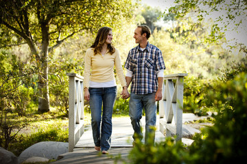 Caucasian couple walking on outdoor wooden bridge