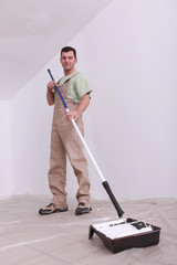handyman painting with a longhandled cylinder