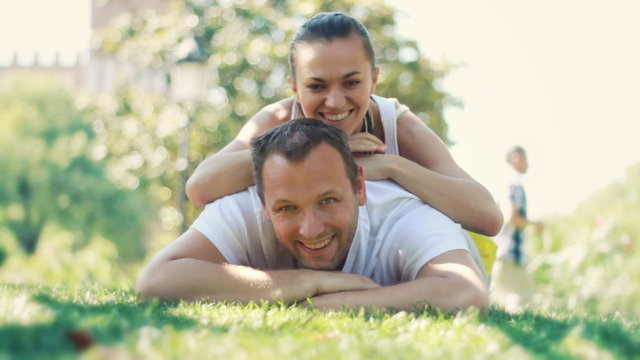 Woman lying on man back on the green grass