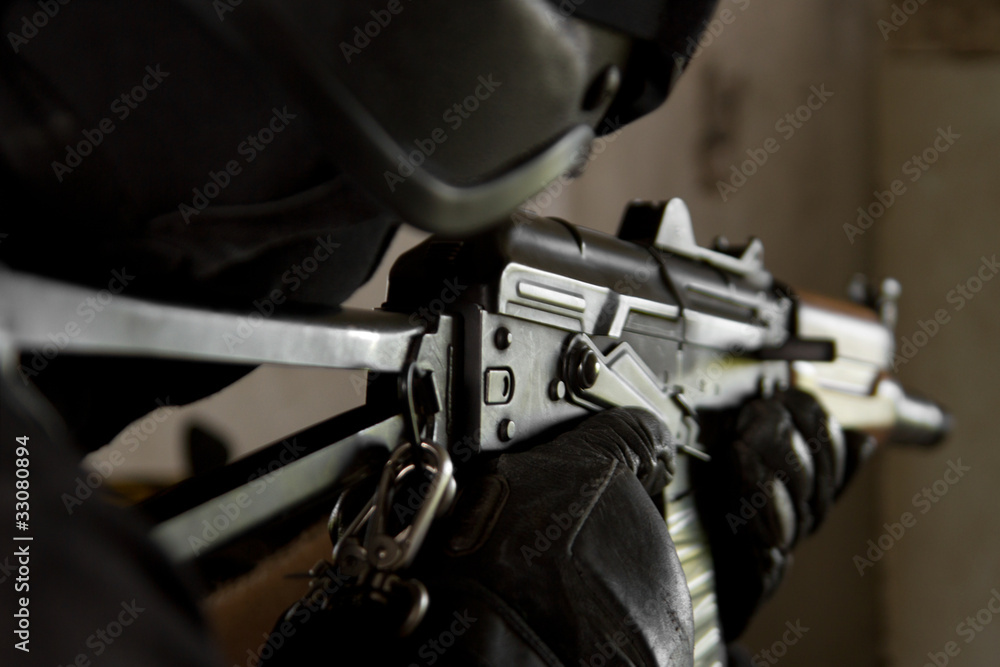 Poster Armed soldier with AK-47 machine gun aiming the target.Military man in heavy combat ammunition targeting on enemy with automatic rifle.Shooter in bulletproof helmet with gun in hands