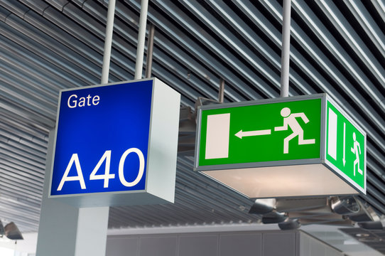 Green emergency exit sign,and blue gate sign in airport