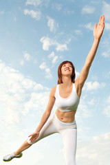 Junge sportliche Frau balanciert vor blauem Himmel