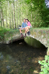 Couple sitting on a bridge in forest