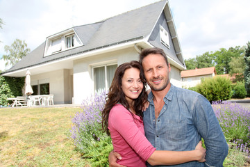 Happy couple standing in front of new home