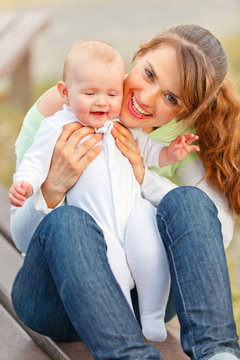 Happy mother holding smiling adorable baby girl in hands.