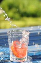 Tomatenscheibe fällt in Wasserglas