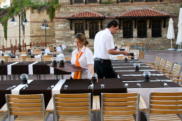 Waitress and waiter preparing restaurant.