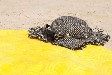 Straw Hat, sunglasses and a towel on the beach