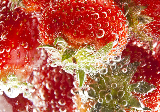 heap of strawberries in water with bubbles