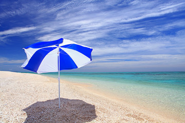 真っ白い砂浜に立つビーチパラソル
