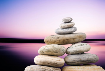 Pebbles stack in peaceful evening with smooth ocean background.