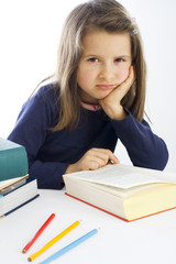 sechsjähriges Mädchen sitzt lustlos vor einem Buch (mr)