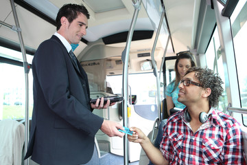 A young controller controlling passengers in a bus. © auremar