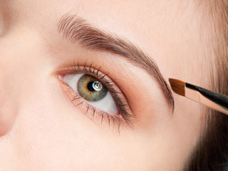 Beautiful young adult woman applying cosmetic shadow brush