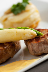 Nahaufnahme von weißem und grünem Spargel auf Schweinefilet