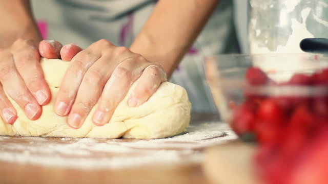Female hands in flour kneading dough on table, dolly shot